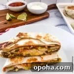 Quick Summer Dinner Recipes for Lazy Weeknights 8 copycat crunchwrap cut in half with a serving board with bowls of sour cream, salsa, a bottle of Tapatio, and lime slices in the background.