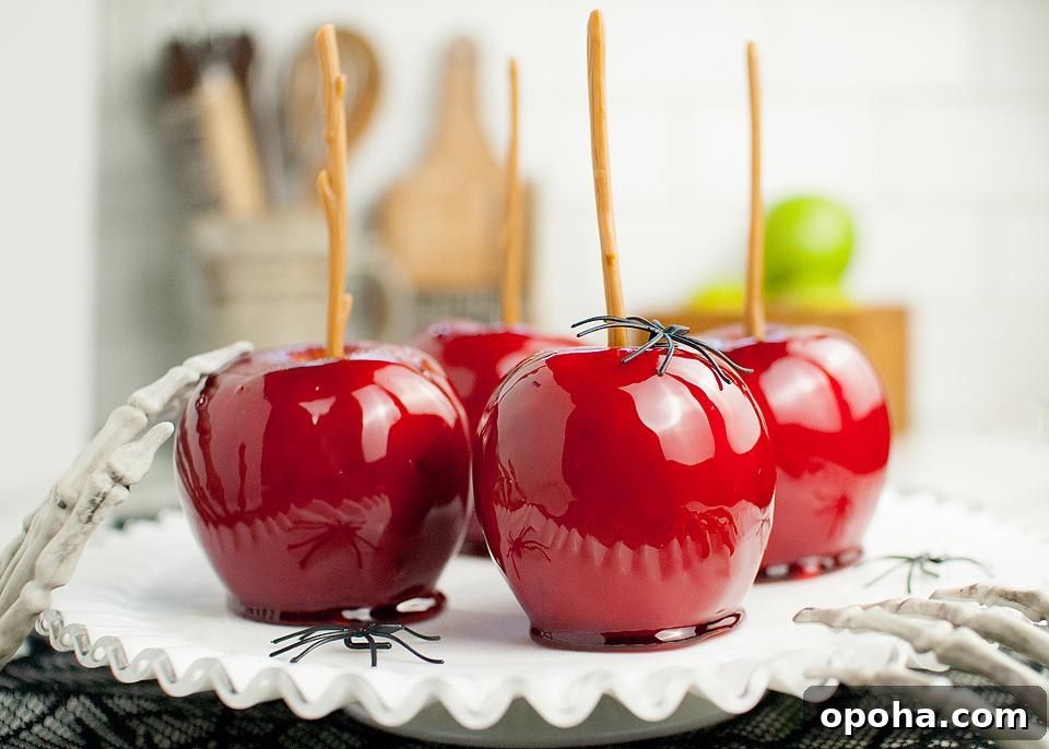 18 Spooky Halloween Movie Night Snacks to Delight Your Guests 7 Easy Candy Apples on a white tray with fake spiders