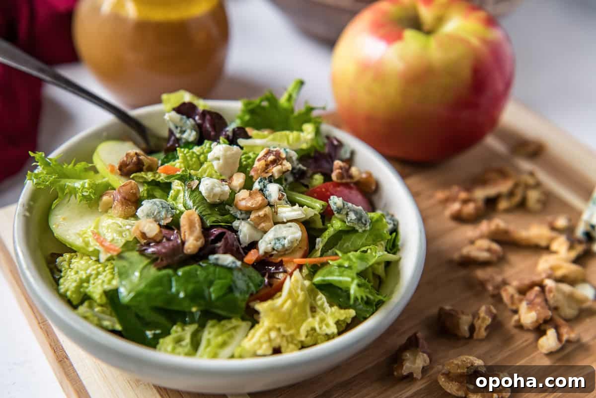 Apple, Walnut & Gorgonzola Cabbage Salad Recipe 4 A serving of Apple Cabbage Salad in a white bowl next to apples.