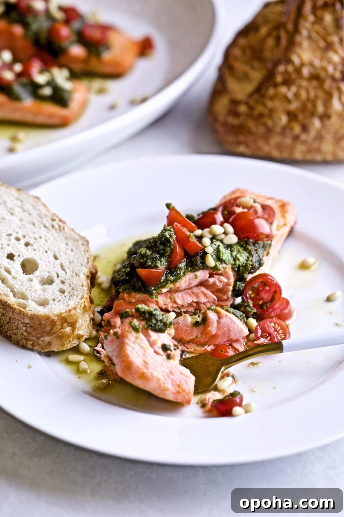 Oven-Baked Salmon with Fresh Basil Pesto 8 plated salmon pesto fillet with a bite taken out to show the perfectly cooked and flaky interior.