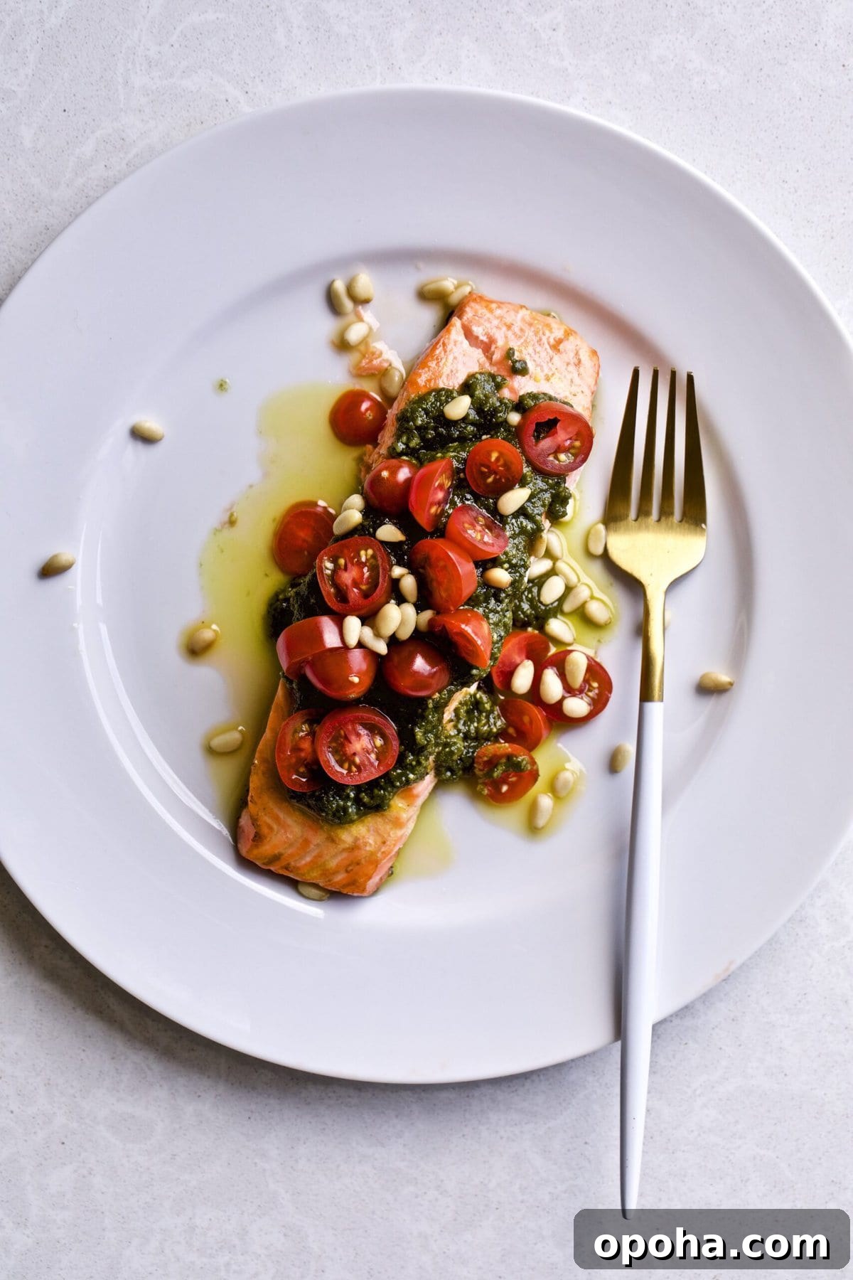 Oven-Baked Salmon with Fresh Basil Pesto 9 Salmon on a plate with pesto, tomatoes, garnish, and a fork.