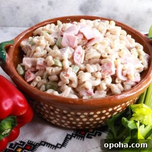 Mexican Macaroni (Ensalada de Coditos) — Creamy Cold Pasta Salad 8 Ensalada de Coditos in a brown bowl with a red bell pepper and stalk of celery beside it.