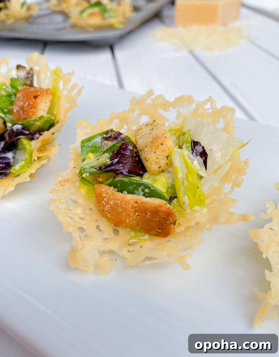 Mini Parmesan Caesar Salad Cups: Crispy Baked Appetizer 2 Parmesan cheese crisps filled with a caesar salad on a white plate.