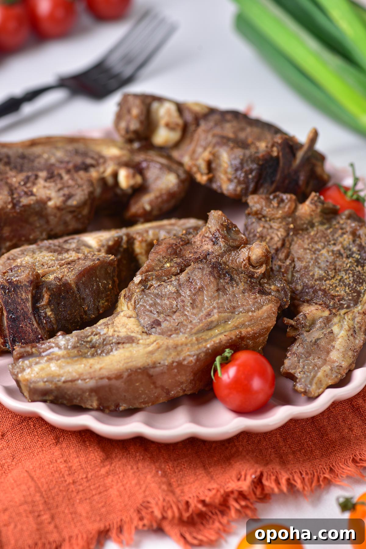 the finished lamb chops recipe garnished with cherry tomatoes and served on a white plate