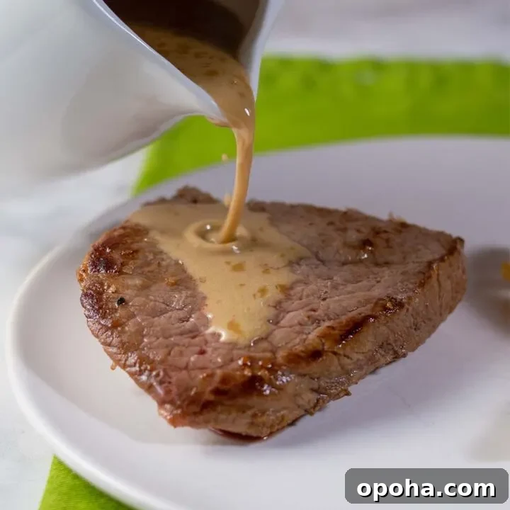 Whiskey sauce being poured onto a piece of sirloin steak