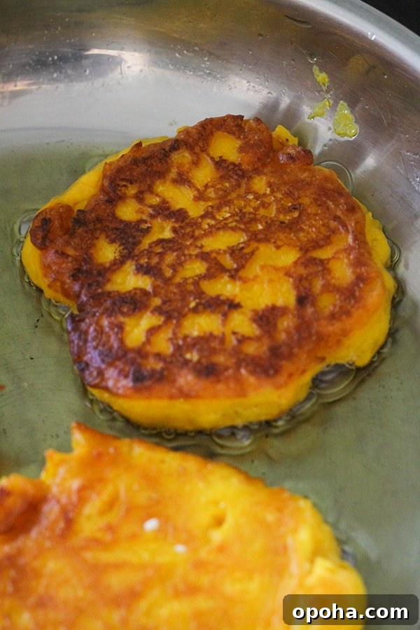 Crispy Pumpkin Fritters with Maple Cinnamon Glaze 9 pumpkin fritter being cooked in a frying pan.