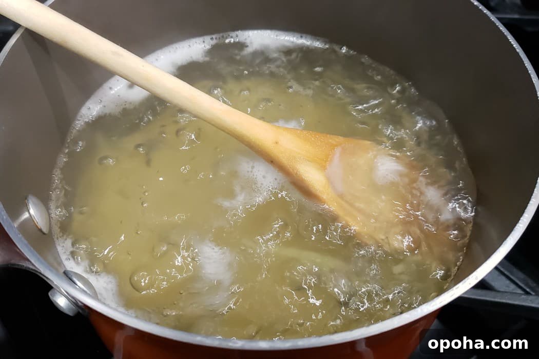 linguine boiling in a pan with a wooden spoon.