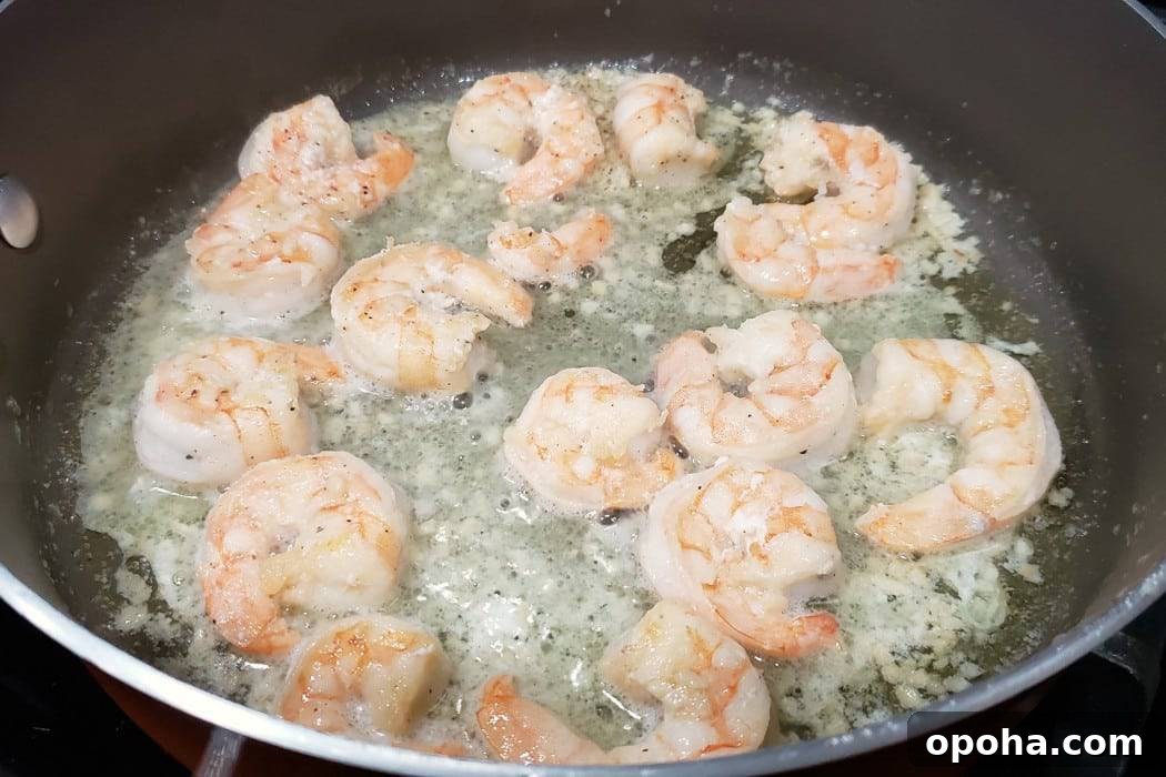 shrimp, garlic, salt, and pepper frying in a pan.