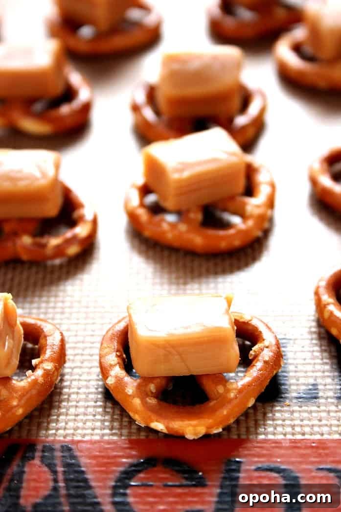 How to make pretzel candy with caramel. Mini pretzels with a square of caramel on silicone baking mat.