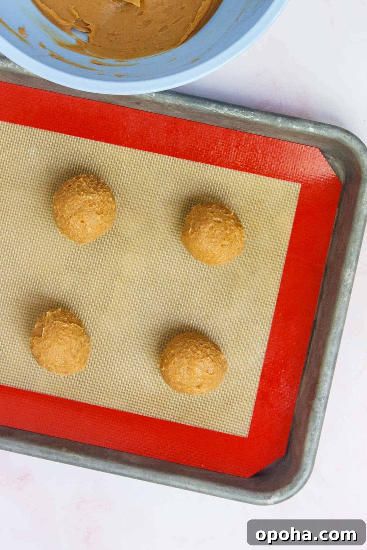 3-Ingredient Peanut Butter Blossom Cookies — Quick Holiday Treat 7 Cookie dough balls spaced evenly on a lined baking sheet.