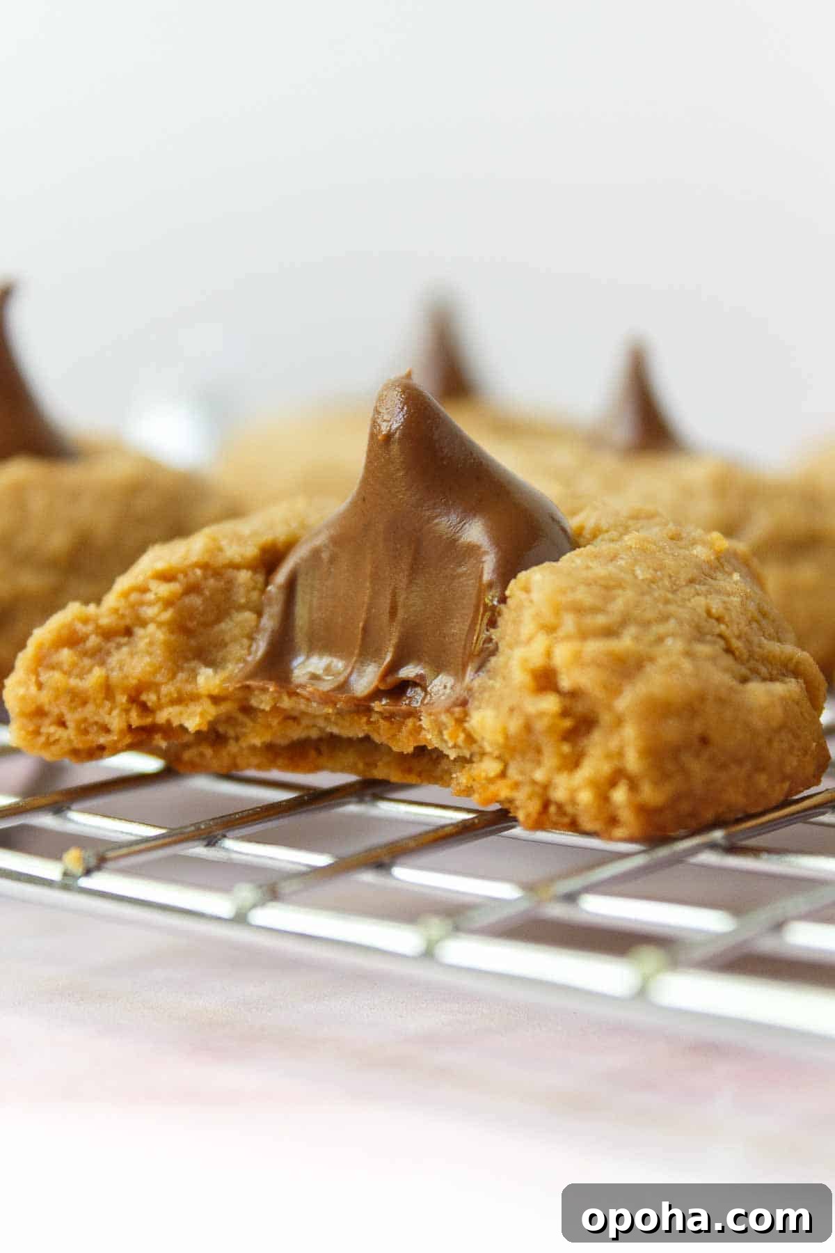 3-Ingredient Peanut Butter Blossom Cookies — Quick Holiday Treat 10 A bite is taken out of a peanut butter blossom cookie to show the creamy inside.