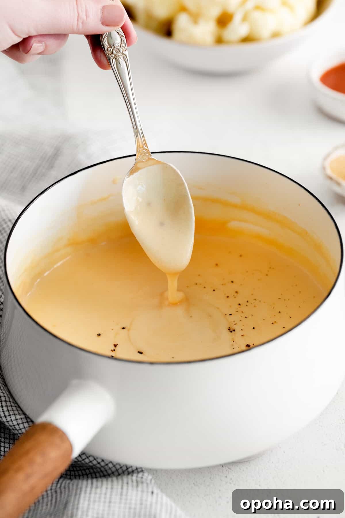 Looking for a classic cheddar cheese sauce recipe? This cheese sauce is perfect for dipping chips, topping veggies, or mixing with noodles. It's truly an all-purpose sauce. cheese sauce in pot.