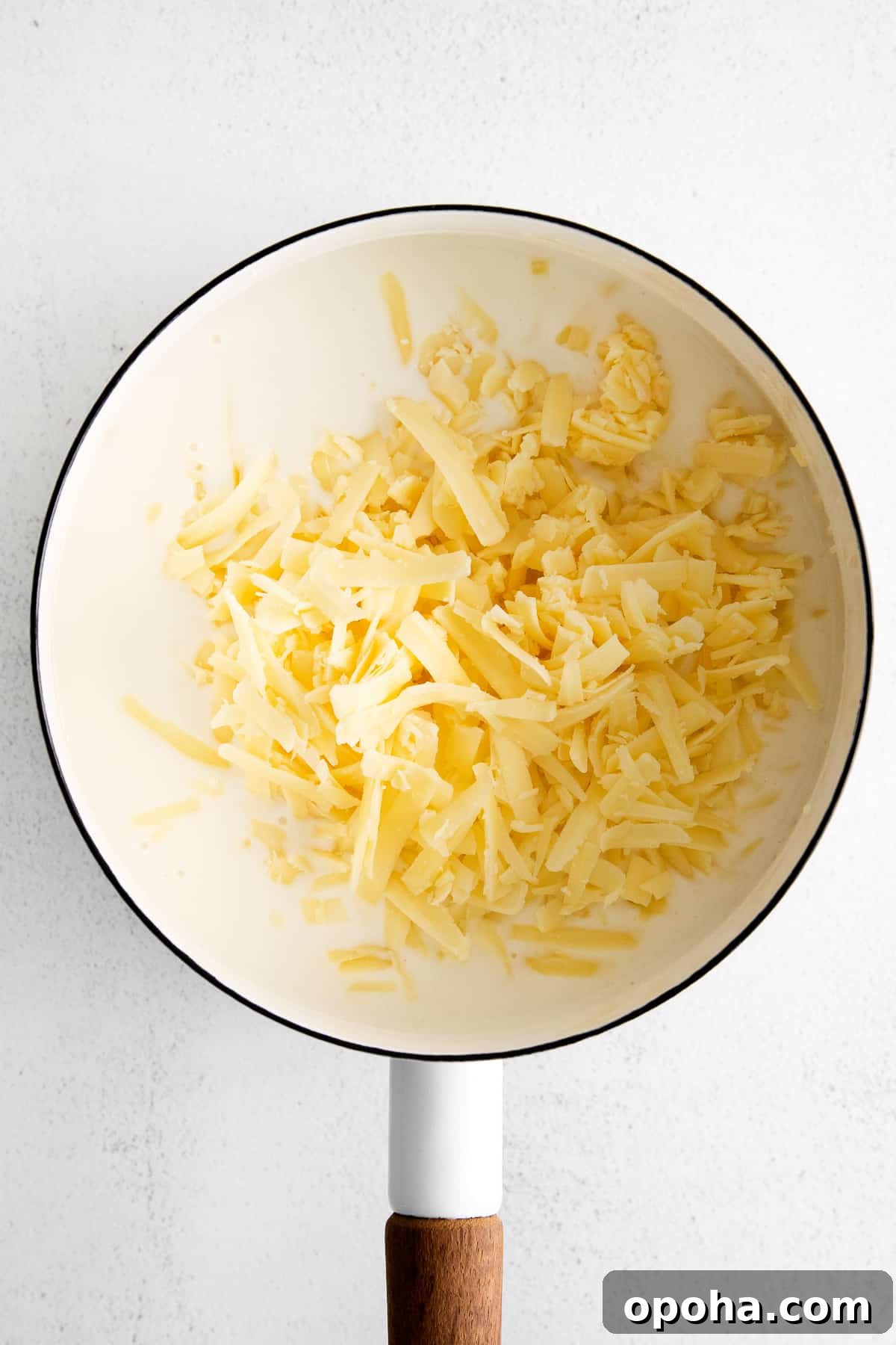 Looking for a classic cheddar cheese sauce recipe? This cheese sauce is perfect for dipping chips, topping veggies, or mixing with noodles. It's truly an all-purpose sauce. adding cheese to pot.