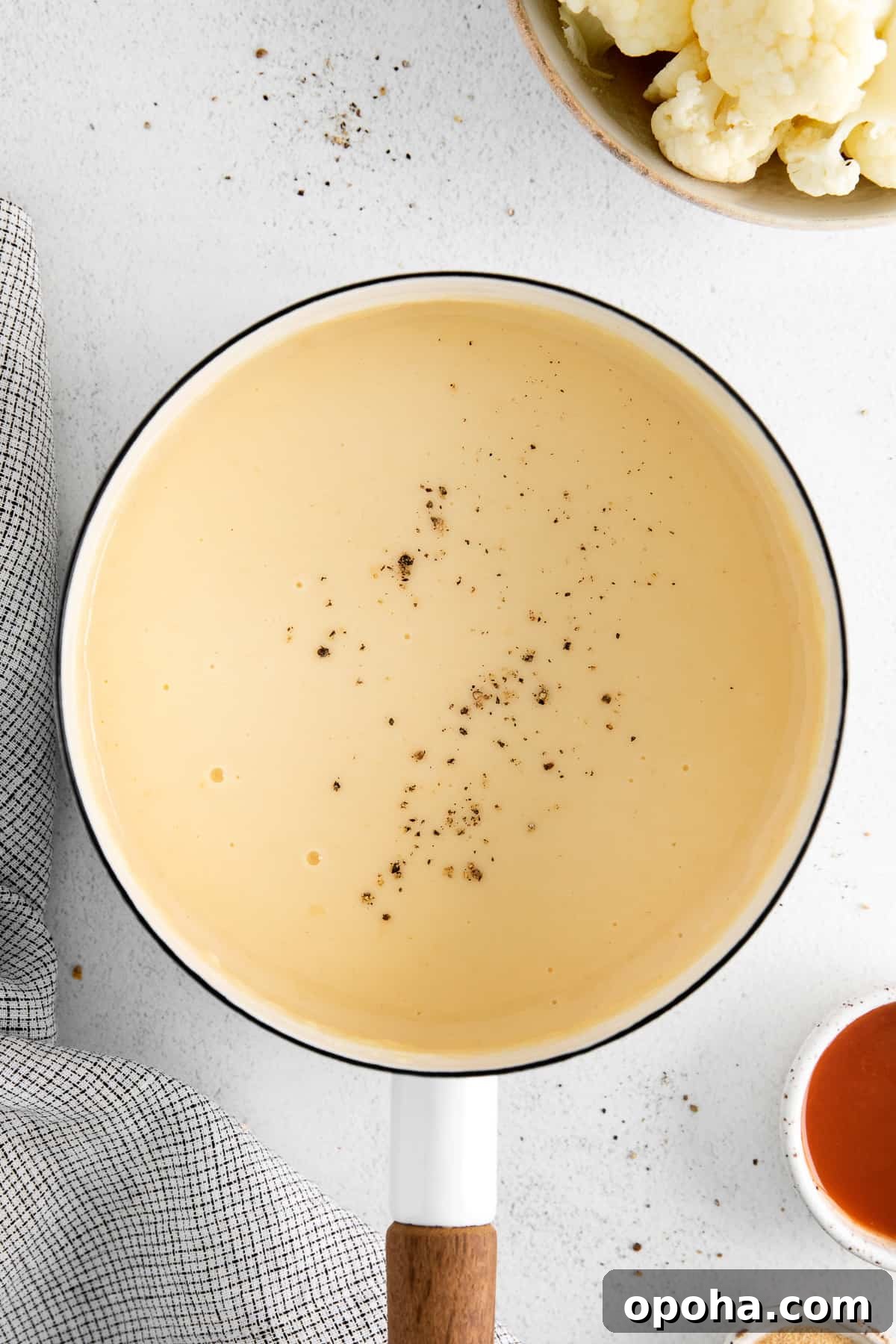 Looking for a classic cheddar cheese sauce recipe? This cheese sauce is perfect for dipping chips, topping veggies, or mixing with noodles. It's truly an all-purpose sauce. cheddar cheese sauce with pepper on top in pot.