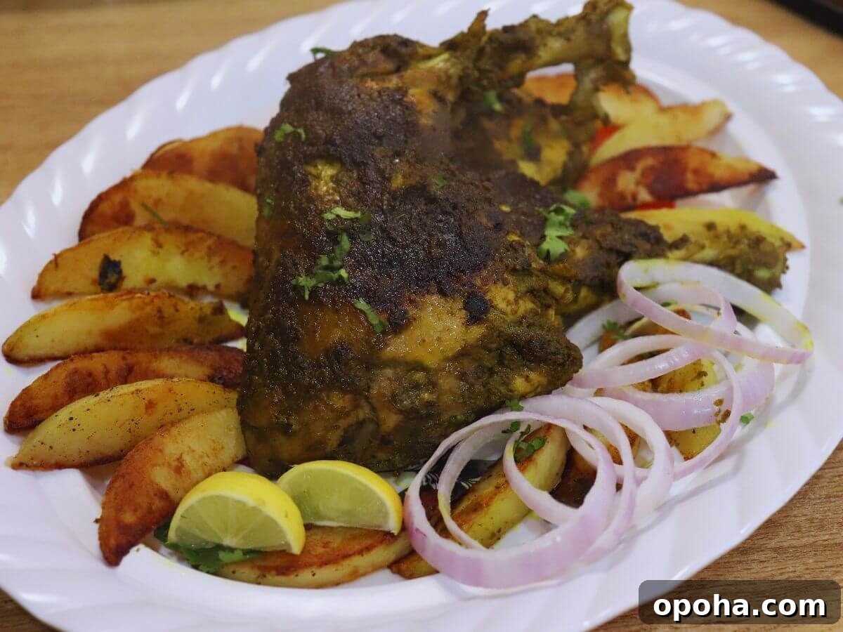 Goan Chicken Cafreal (Galinha Cafreal) Recipe — Authentic Spice Rub 2 close-up of chicken cafreal served in a white colored plate with roasted potato wedges, onion rings and lemon wedges.
