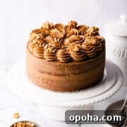 Decadent Coffee and Walnut Cake Recipe for Coffee Lovers 14 coffee and walnut cake topped with buttercream and nuts on a white cake stand.
