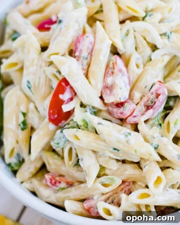 Overhead photo of a white glass serving bowl filled with a pasta salad made with tomatoes and fresh asparagus