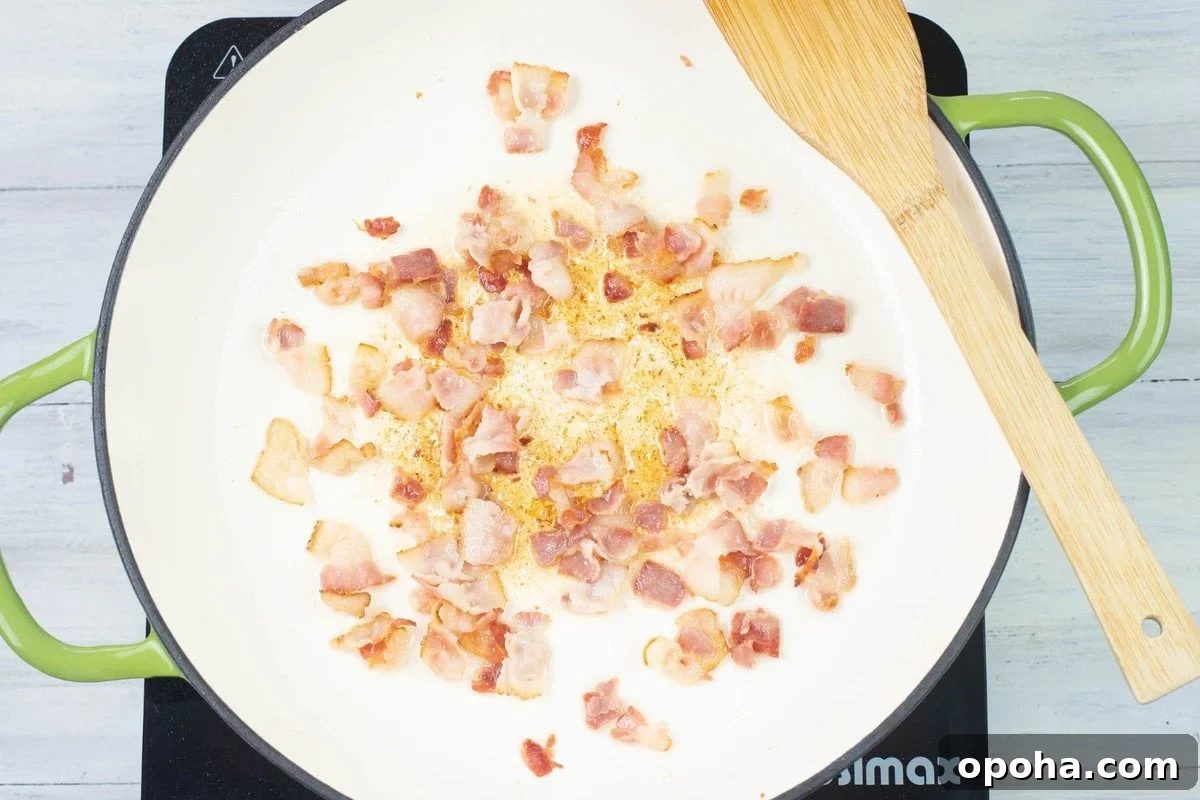 Sautéed Asparagus, Tomatoes & Bacon Skillet Recipe 5 Overhead looking down into a cast iron skillet at cubed bacon being fried until golden.