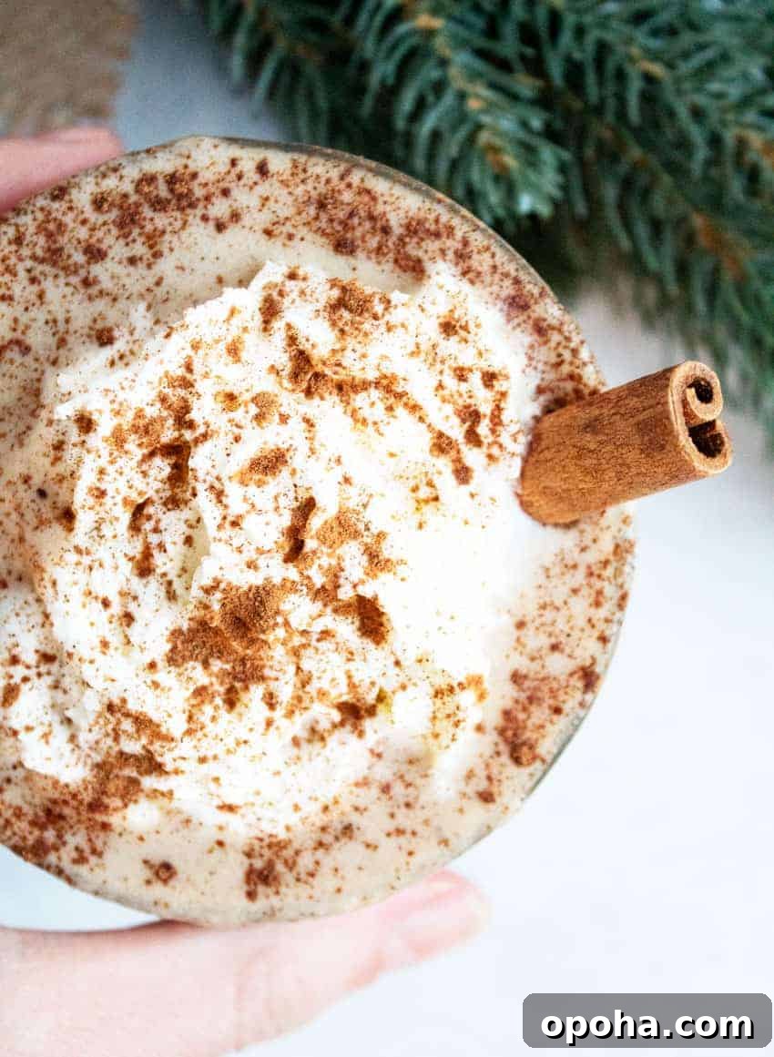 Keto Pumpkin Chocolate Chip Cookie Recipe for Fall Treats 20 hand holding a glass of keto eggnog next to greenery