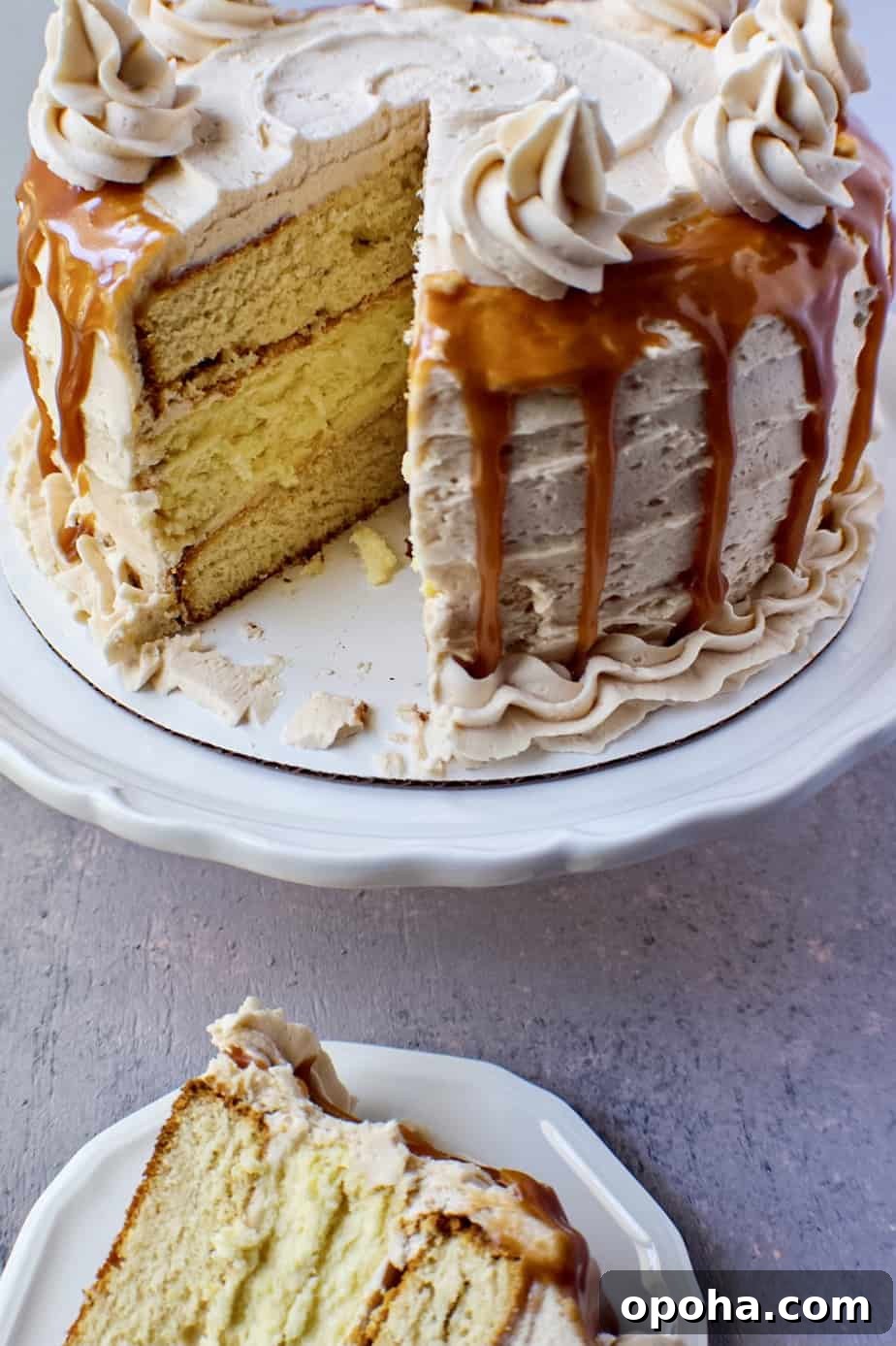 close up of slice caramel cheesecake layer cake on white cake stand.