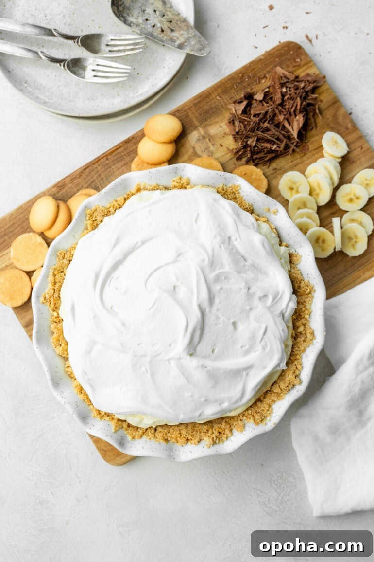 Nilla Wafer Banana Pudding Pie Recipe with Creamy Filling 5 a photo of a whole creamy banana pudding pie with slices of banana sitting next to it and several Nilla Wafars.