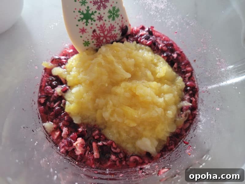 crushed pineapple mixing into shredded cranberries for cranberry dessert salad