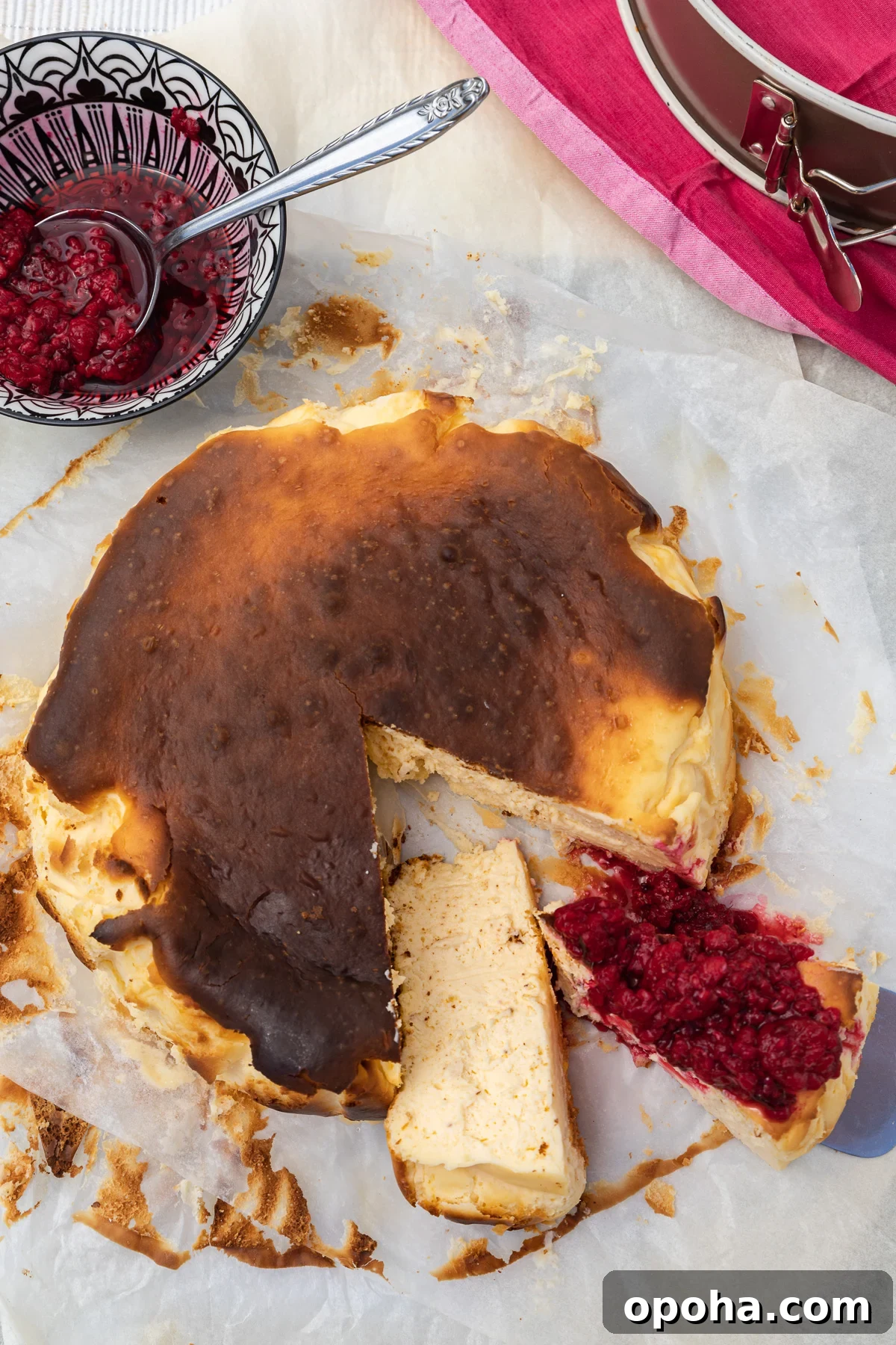 Basque Cheesecake with Greek Yogurt: Creamy Burnt-Surface Recipe 2 A San Sebastian cheesecake from above with pieces cut out and raspberries on the top of one piece