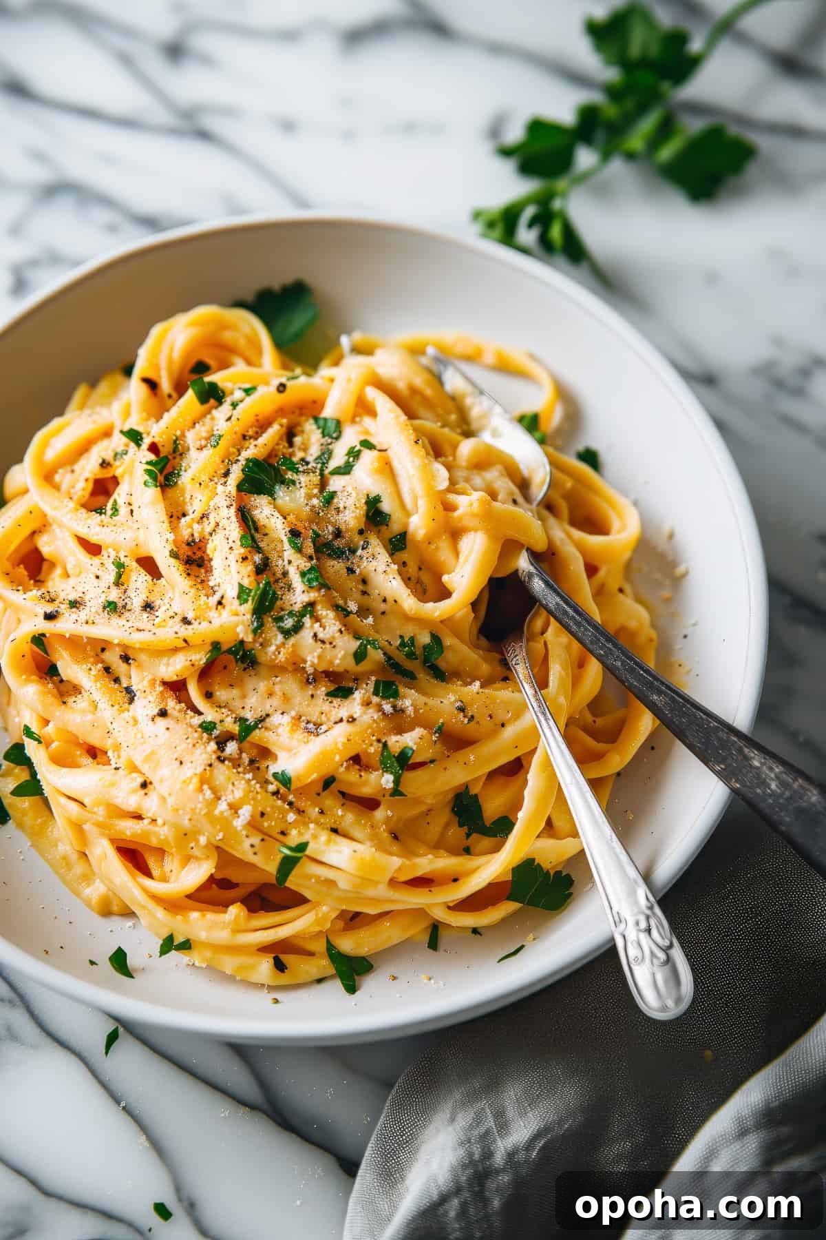 This roasted cauliflower & pumpkin fettuccine Alfredo is the perfect cosy pasta night in. A quick dinner of noodles snuggled into creamy roasted cauliflower sauce with sweet and earthy roasted pumpkin and deep flavoured mushrooms and juicy figs. Creamy pumpkin alfredo with parmesan cheese in a white bowl.