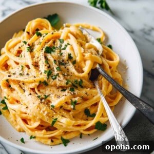Creamy Pumpkin Alfredo Pasta Recipe for Fall Comfort 4 Creamy pumpkin alfredo with parmesan cheese in a white bowl.