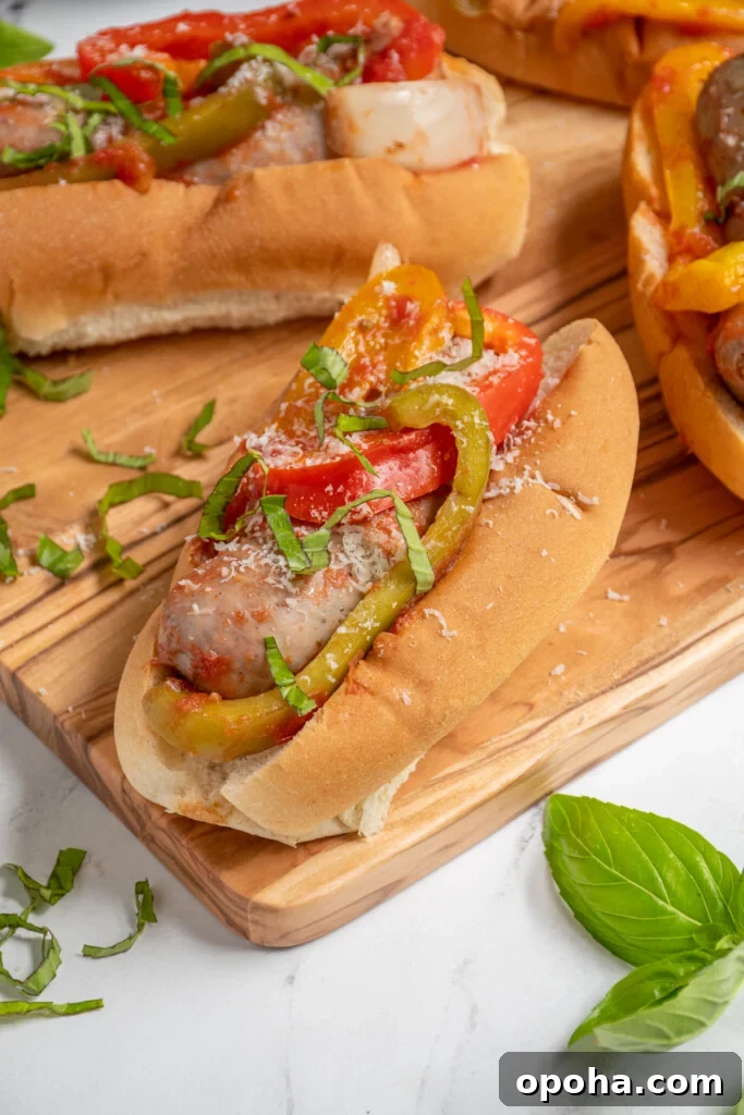 Slow Cooker Sausage and Peppers with Onions and Tomato Sauce 2 An Italian Sausage with peppers and onions in a bun topped with fresh basil and grated parmesan cheese.