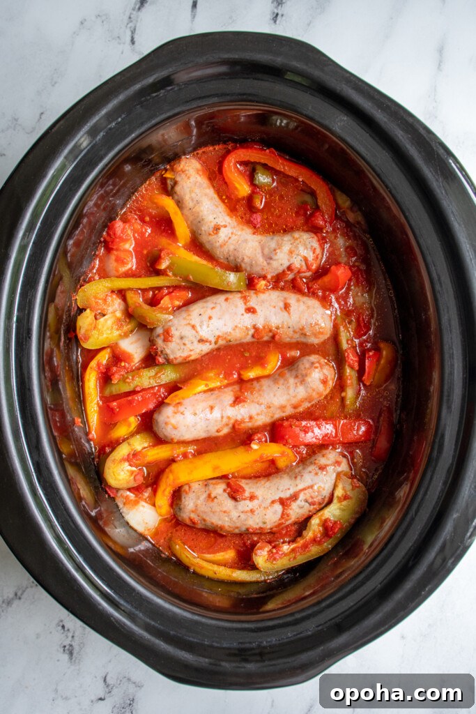Slow Cooker Sausage and Peppers with Onions and Tomato Sauce 6 Overhead view of freshly cooked Italian sausages in the crockpot with sliced bell peppers and onions.