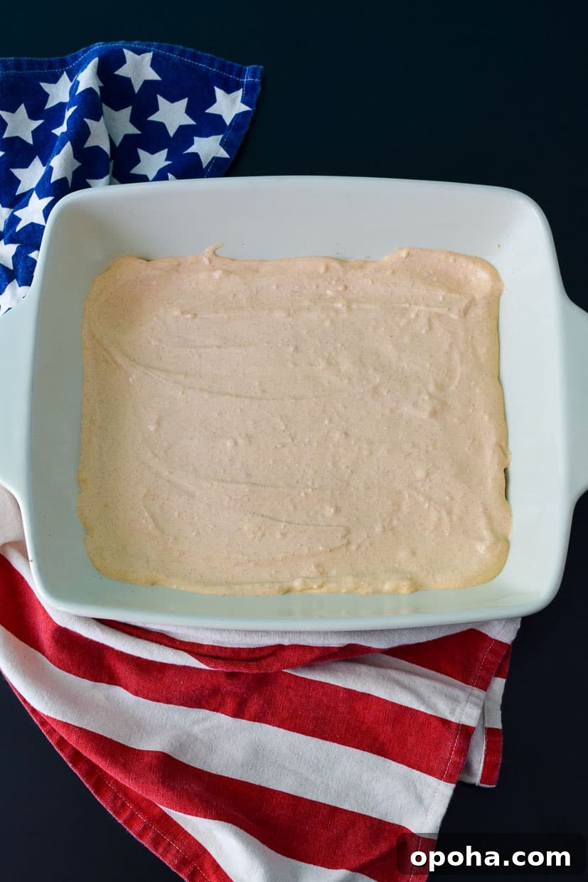 9x13 pan with cream cheese mixture spread over refried beans overhead shot