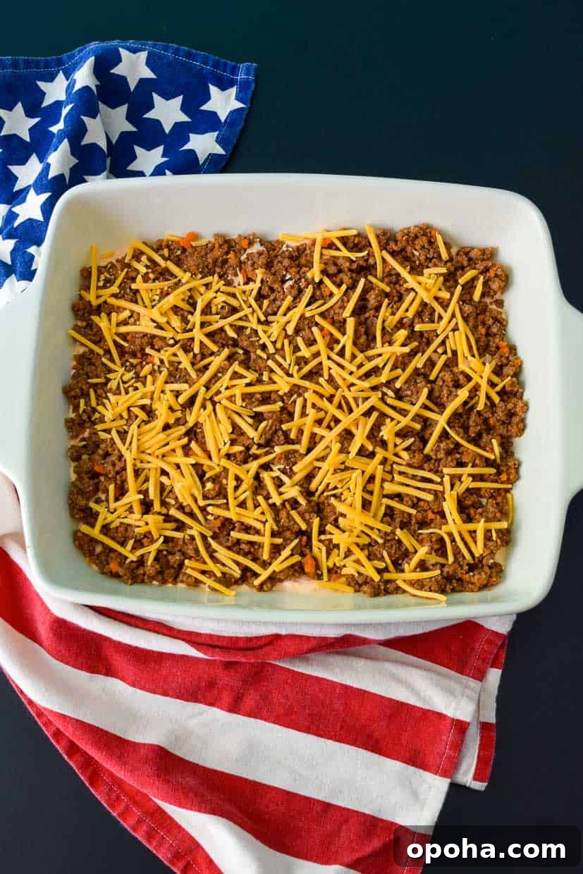 9x13 pan with ground beef topped with shredded cheese overhead shot