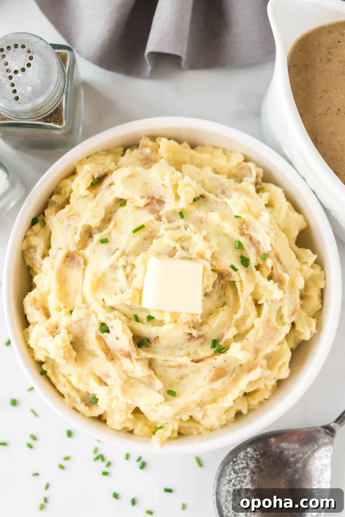 Creamy Mashed Potatoes with Sour Cream and Chives 2 mashed potatoes in a bowl topped with butter and chives