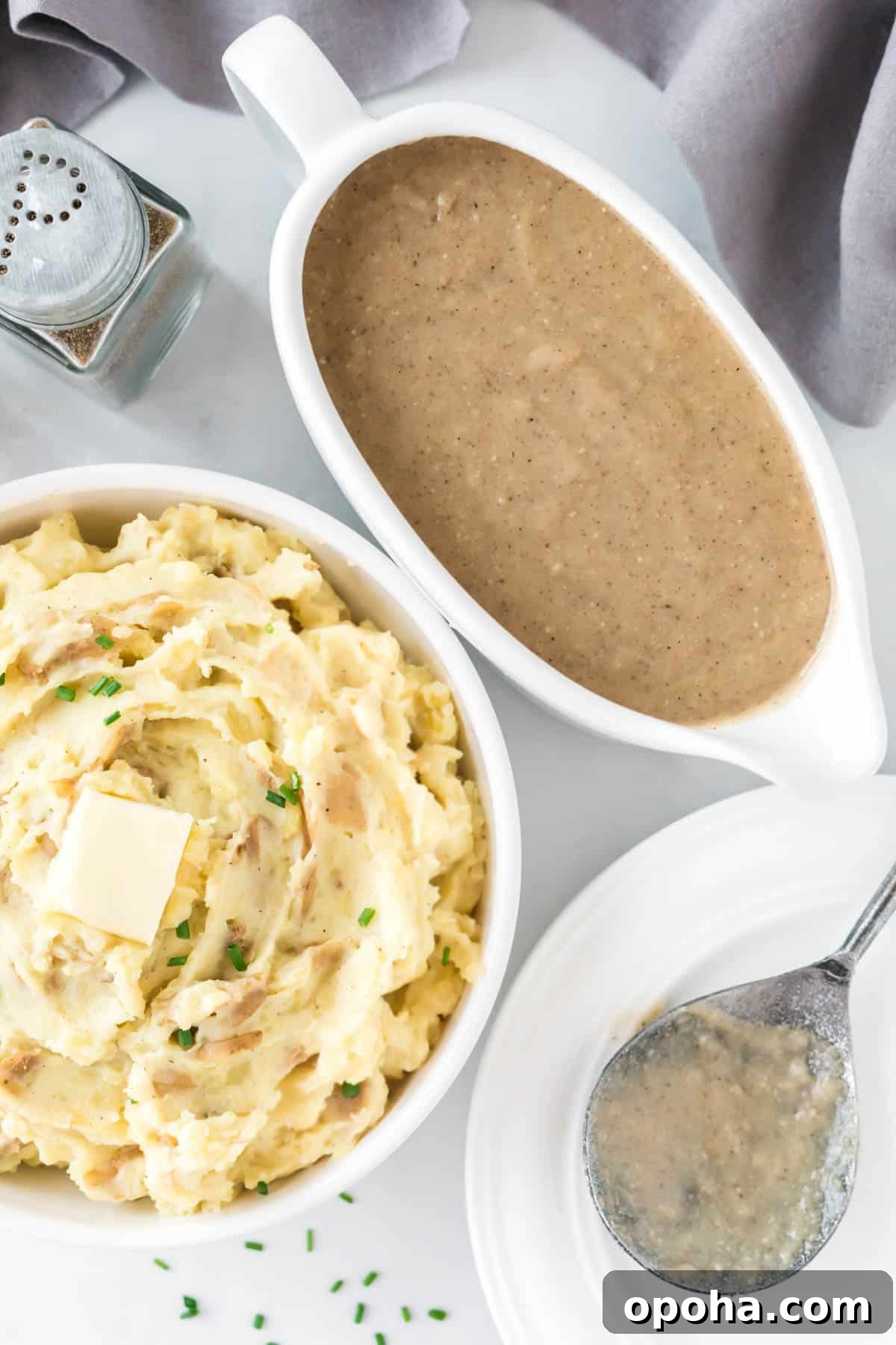 Creamy Mashed Potatoes with Sour Cream and Chives 12 mashed potatoes in a bowl topped with butter next to a gravy boat