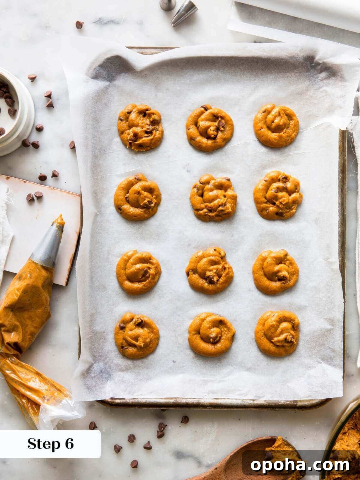 Pumpkin Chocolate Chip Cookie Recipe — Soft, Spiced & Gooey 9 Pumpkin chocolate chip cookie dough piped onto a baking sheet, ready to be baked.