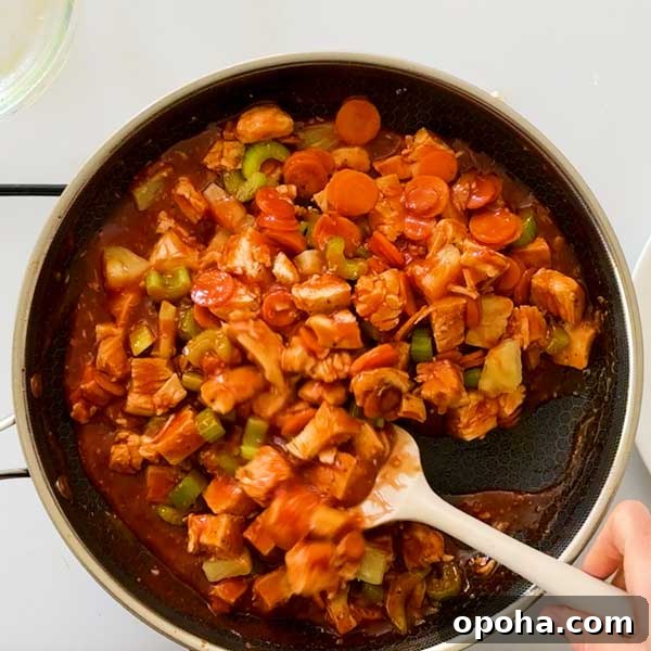 Gluten-Free Sweet and Sour Chicken Made in a HexClad Pan 10 Stirring sweet and sour chicken in a frying pan.