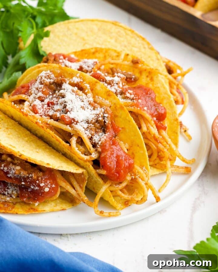 Spaghetti tacos on a plate topped with parmesan cheese.