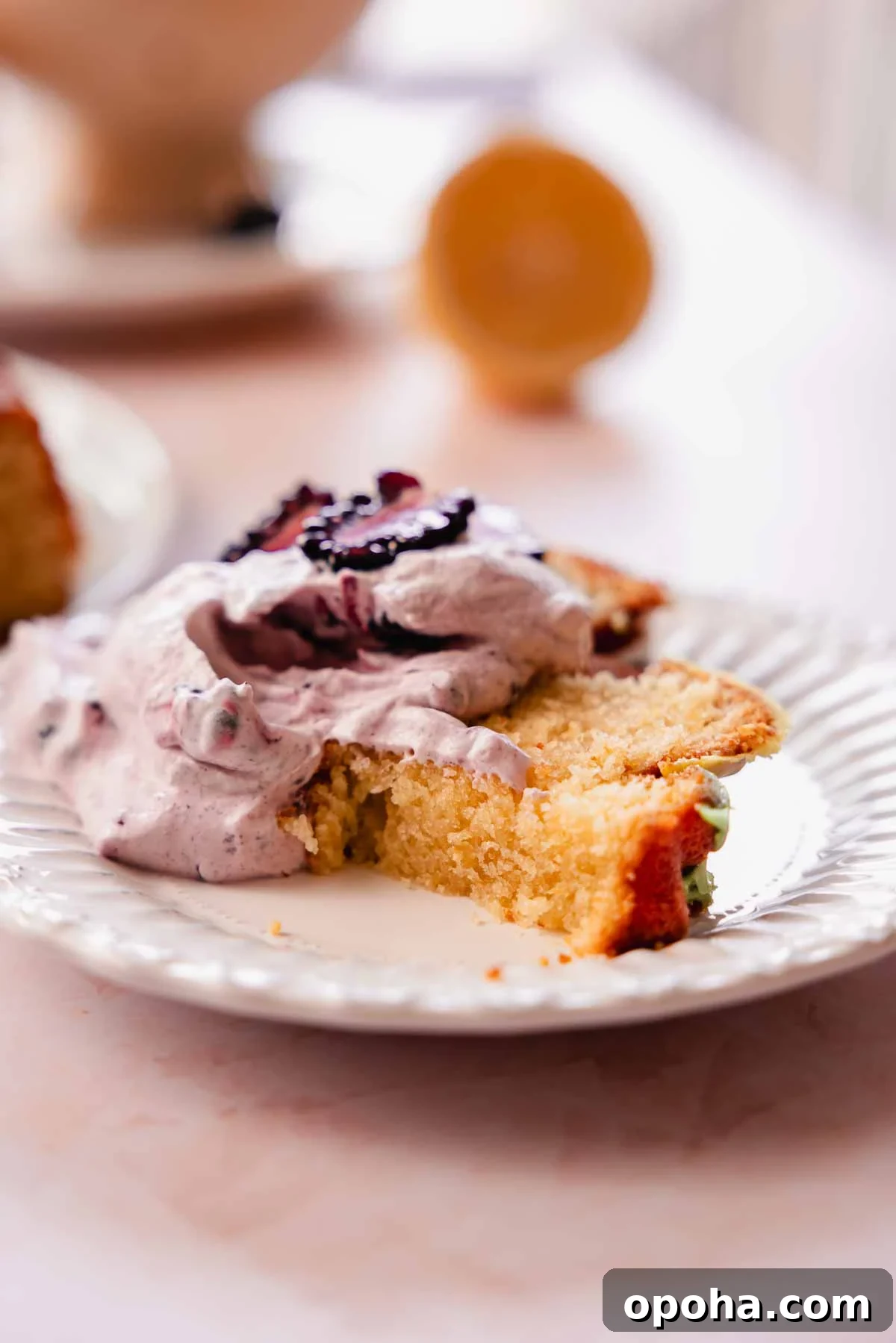slice of bitten lemon pound cake piled with blackberry whipped cream
