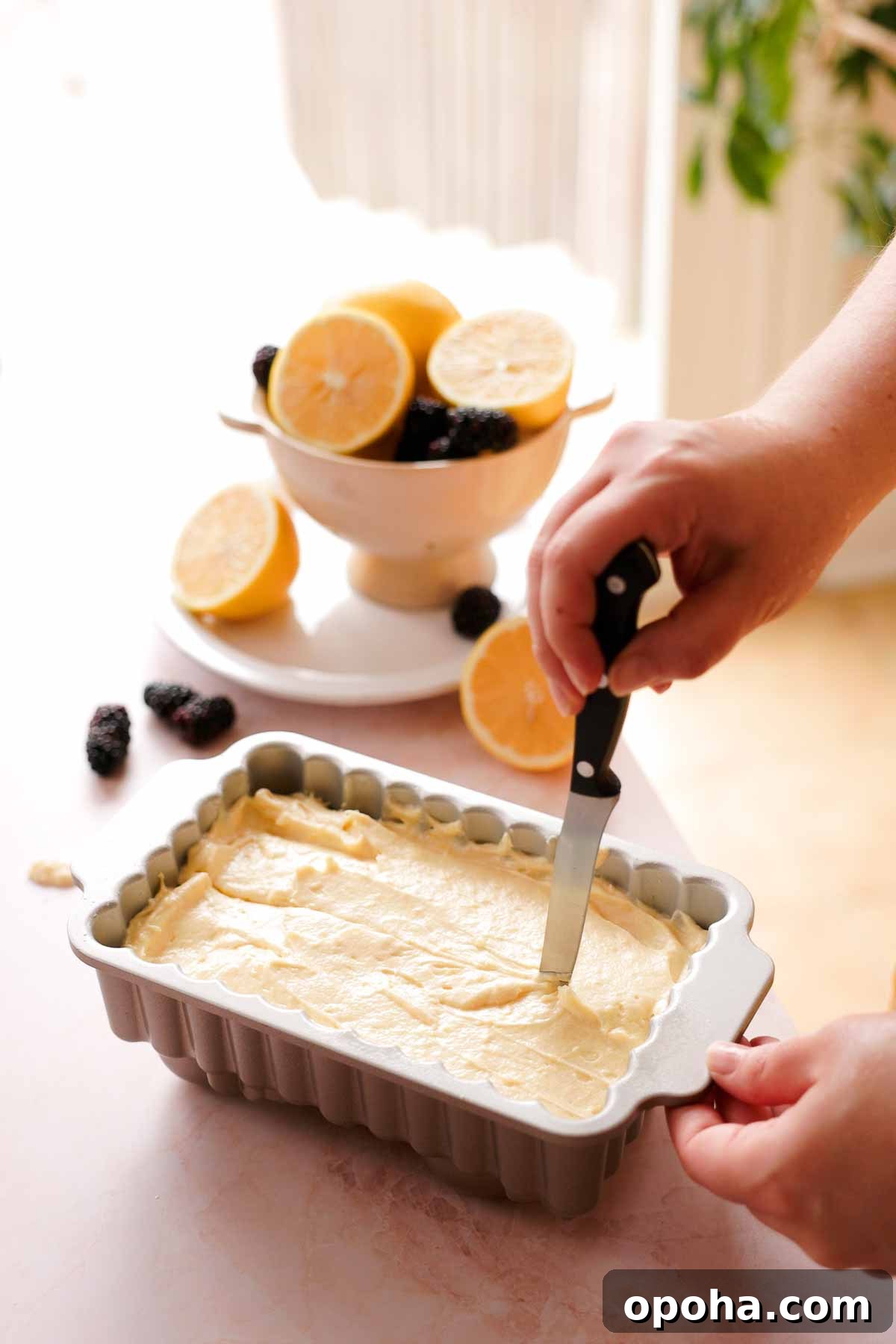 running a knife through the middle of pound cake batter in baking tin