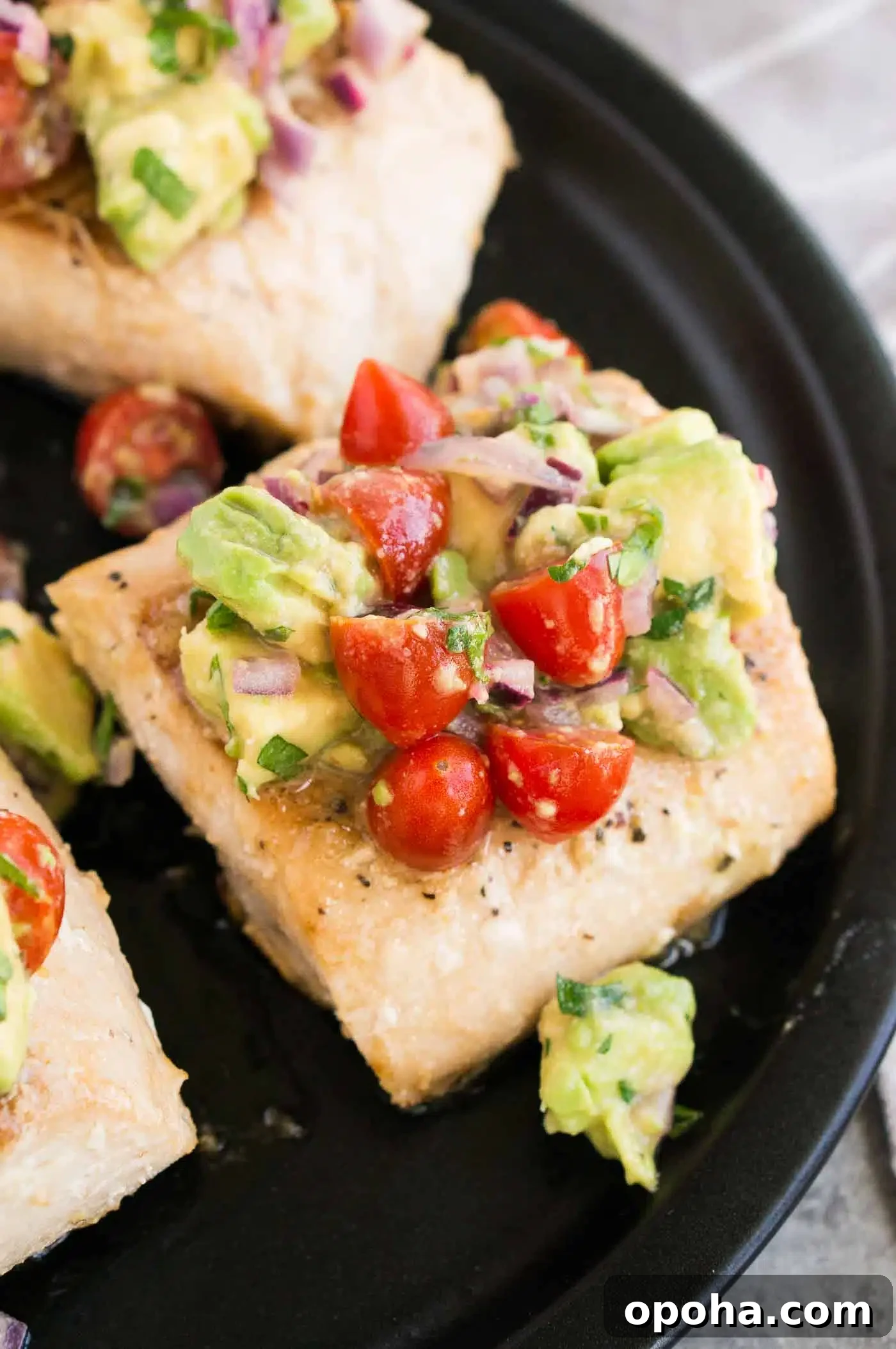 close up image of mahi mahi topped with avocado salsa on a plate 