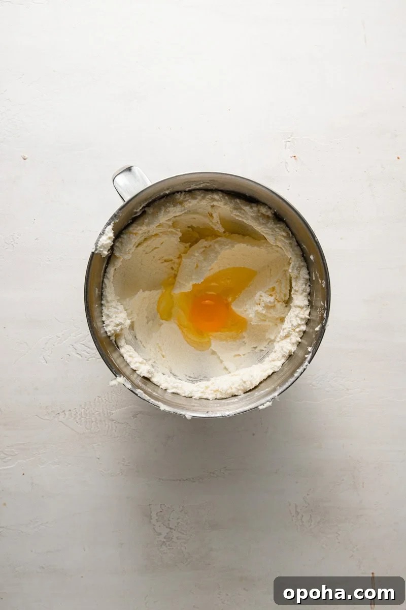 A bowl of a stand mixer with whipped butter and an egg.