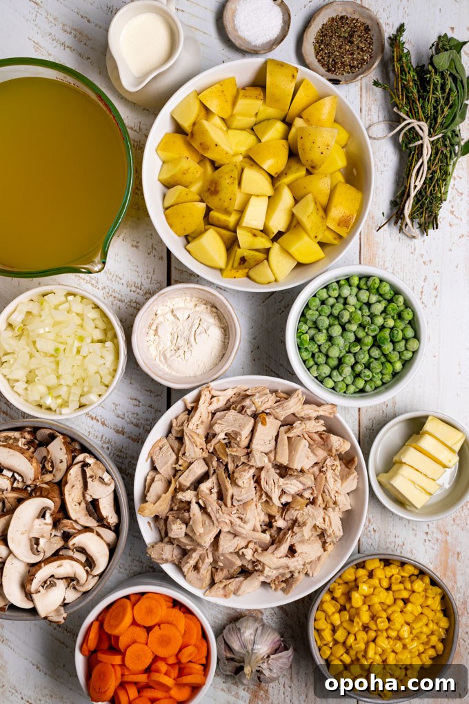 Overhead photo of ingredients in bowls - cut up chicken, frozen peas, cut up potatoes, corn, cut up carrots and mushrooms, diced onion, chicken broth, and an herb bundle. This scene is photographed on a white distressed wood surface. #foodphotogrpahy