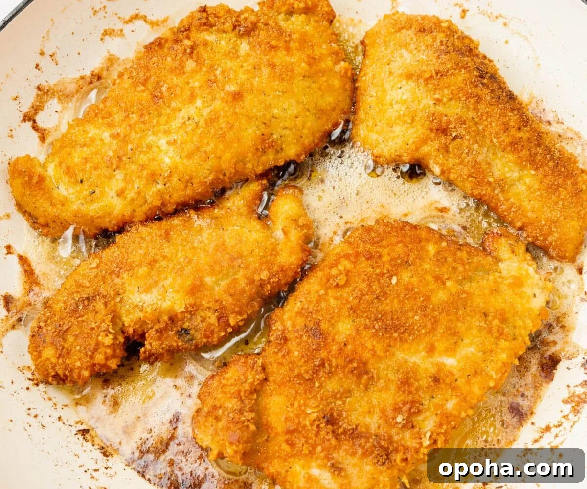 Crispy Gluten-Free Chicken Parmesan Recipe for Dinner 11 Gluten-Free Chicken Parmesan being fried in a skillet.