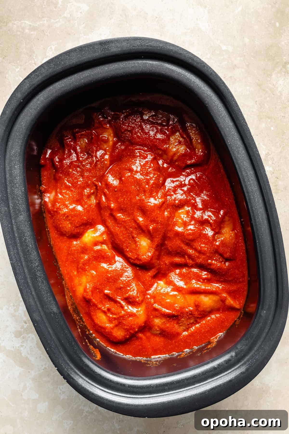 raw chicken breasts with bbq sauce in a slow cooker.
