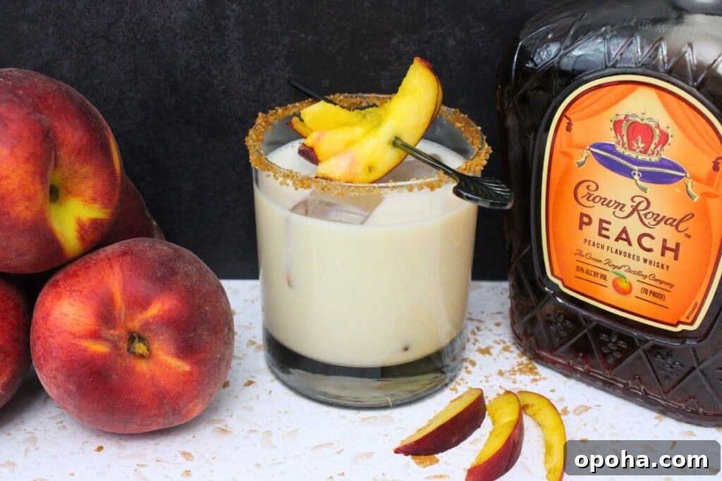 Peach Cobbler Cocktail Recipe with Crown Royal Whiskey 12 peach cobbler cocktail next to crown royal peach whiskey bottle and fresh peaches against a dark background