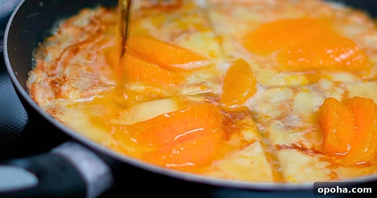 pouring grand marnier over the crepes and orange slices in a frying pan