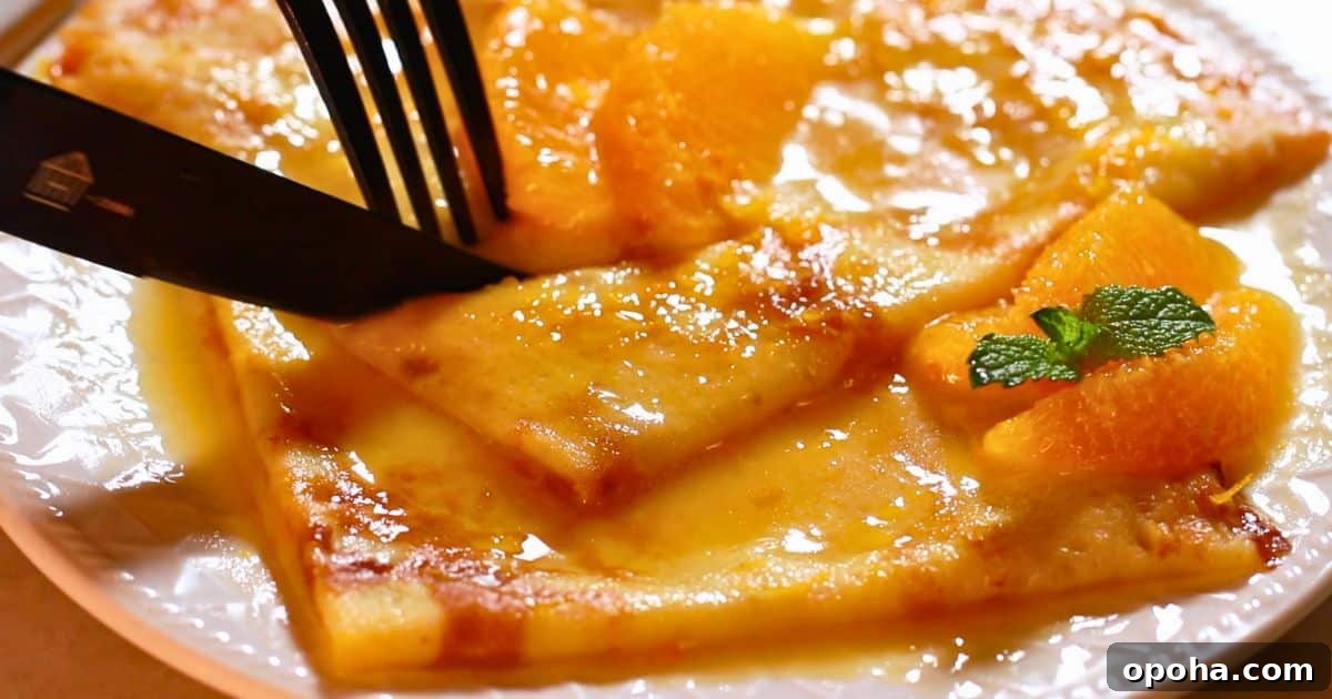 cutting homemade crepes suzette on a plate with a knife and fork