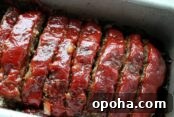Slice meatloaf with a ketchup glaze on top in a loaf pan