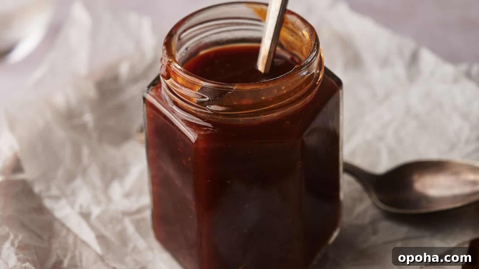 19 Summer Cookout Side Dishes I Make Every Weekend 16 Homemade BBQ sauce in a jar with two spoons by the side.